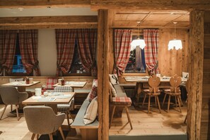 Un restaurante acogedor con muebles de madera, cortinas escocesas y lámparas colgantes.