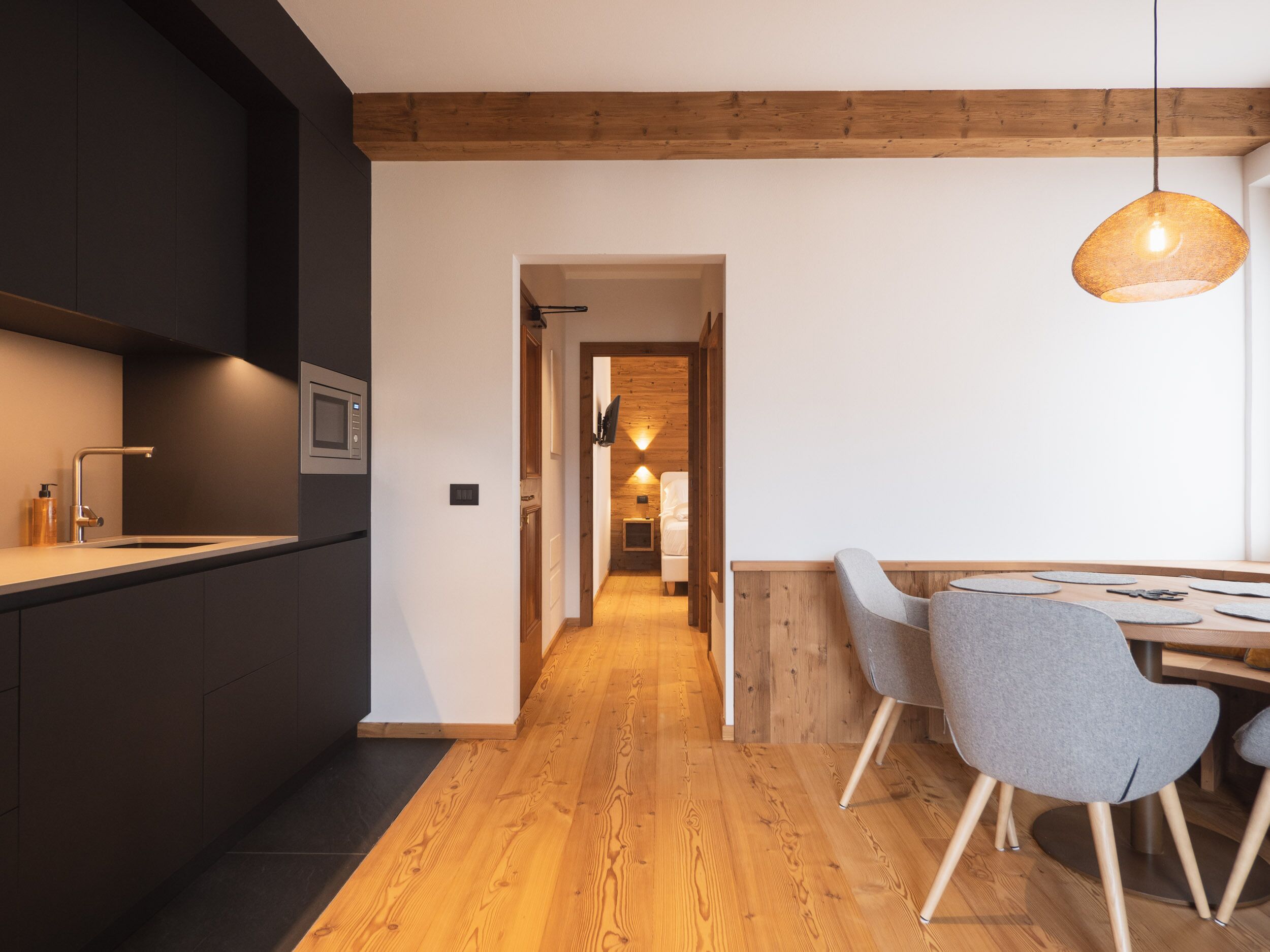 Una cocina moderna con armarios oscuros, suelo de madera y un comedor con una mesa y dos sillas.