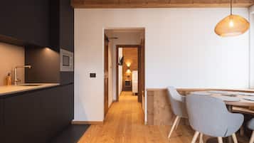 Una cocina moderna con armarios oscuros, suelo de madera y un comedor con una mesa y dos sillas.