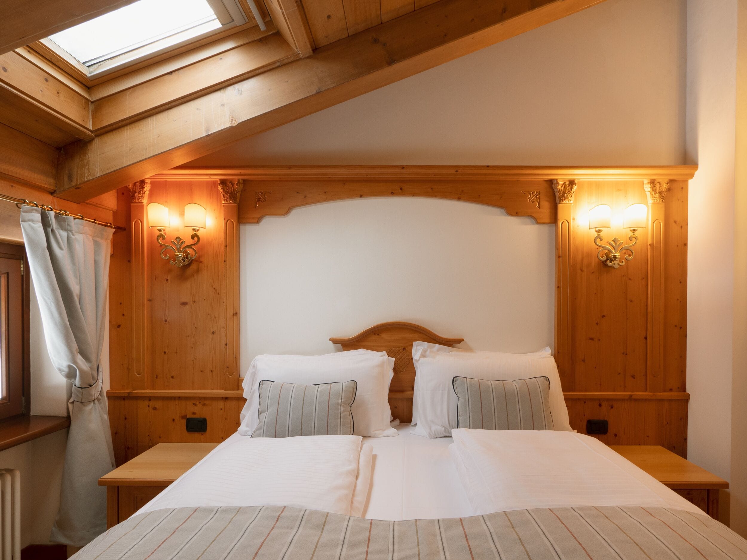 A double bed with a wooden headboard, two bedside tables, and two wall-mounted lamps.