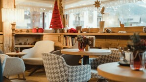 Ein gemütliches Interieur mit Holzwänden, einem runden Tisch, gemusterten Stühlen und einem Weihnachtsbaum.