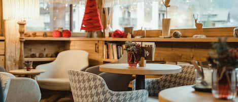 A cozy interior with wooden walls, a round table, patterned chairs, and a Christmas tree.