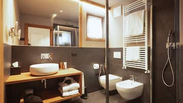 A modern bathroom with a large mirror, a sink, a bidet, and a shower.