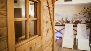 Ein rahmenförmiges Holzfenster mit Blick auf einen Essbereich mit weißen Stühlen und einem Tisch.