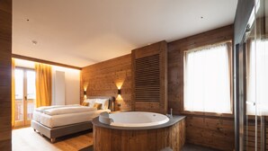 Un dormitorio moderno con dos camas, una bañera de madera grande y un box de ducha de vidrio.