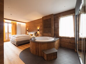 A modern bedroom with two beds, a large wooden bathtub, and a glass shower enclosure. - FIORI Dolomites Experience Hotel (San Vito di Cadore)