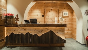 Ein hölzerner Empfangstresen mit Bergmotiv, ein Laptop und ein gerahmtes Bild an der Wand.