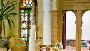A Moroccan-style interior with a tiled floor, wicker furniture, and a table set with a tray of food. - Riad La maison d'à côté (Meknes)