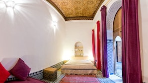 A room with a bed, a sofa, a patterned rug, and a view of the outside. - Riad La maison d'à côté (Meknes)