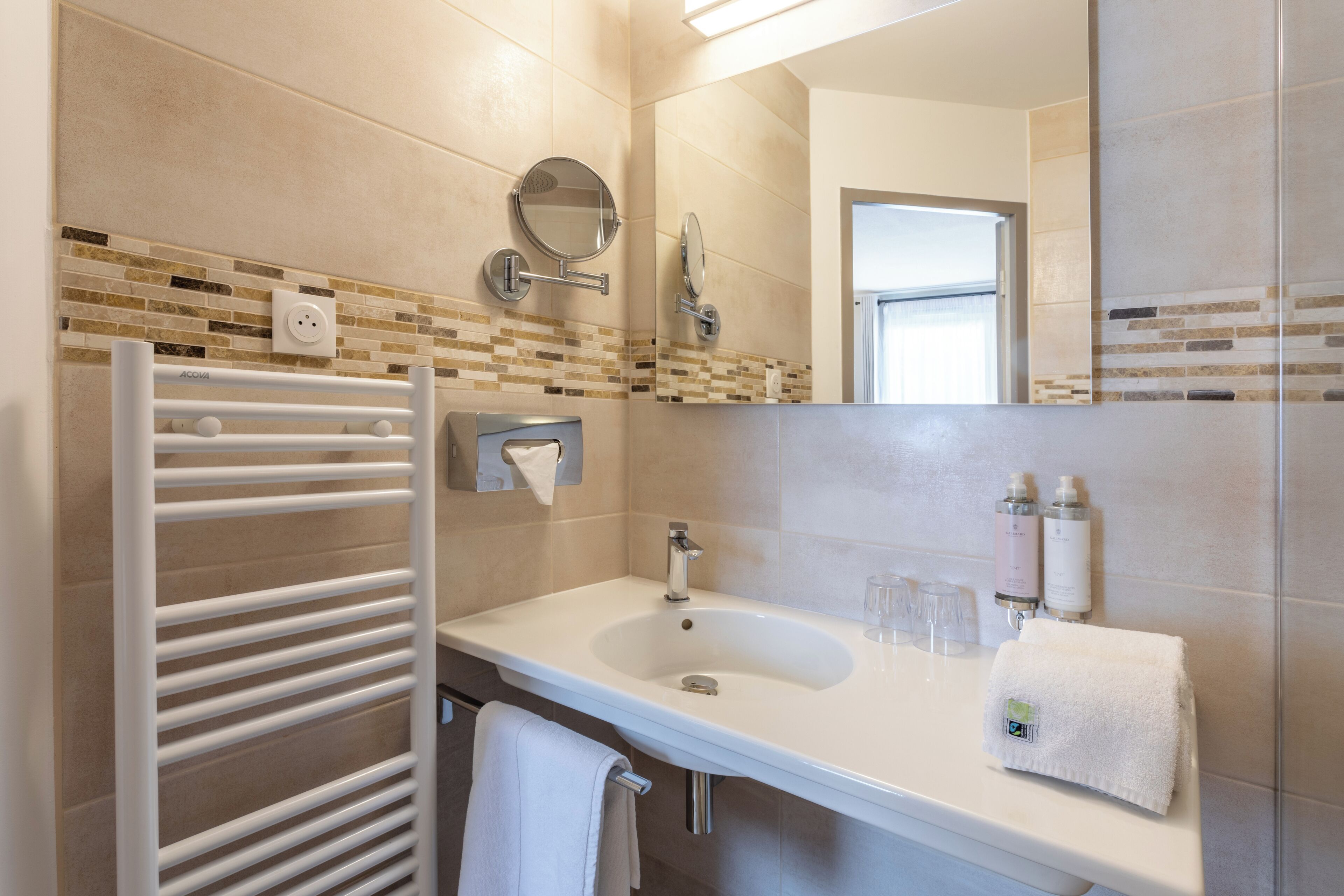 A modern bathroom with a white sink, a towel rack, a mirror, and a glass shower enclosure.