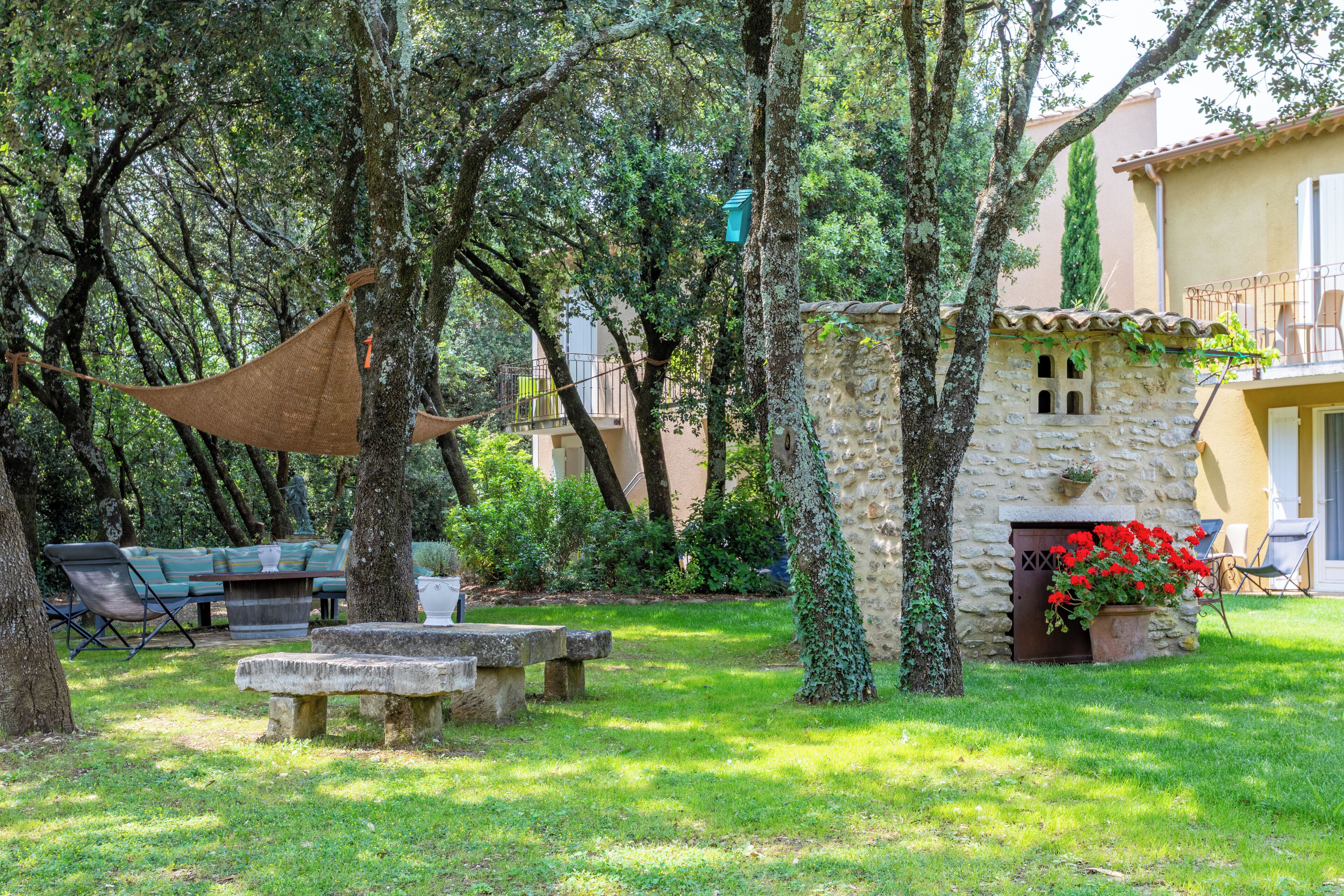 A stone building with a stone fireplace, surrounded by greenery and trees.