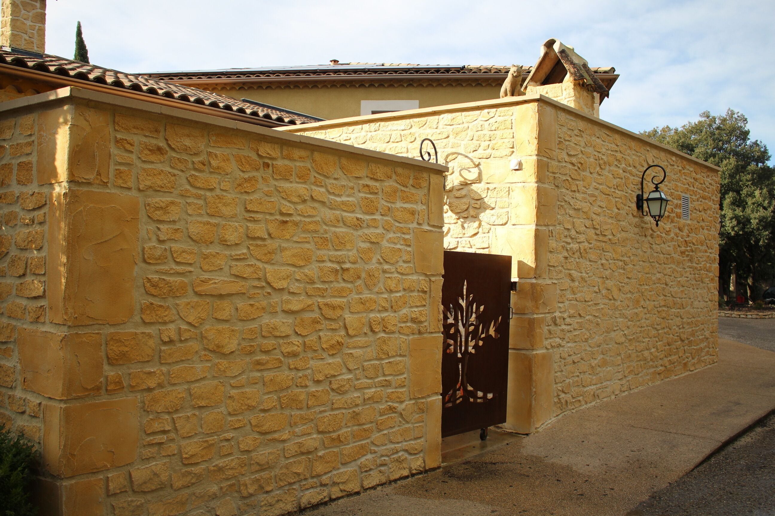 A stone building with a tiled roof and a decorative gate.