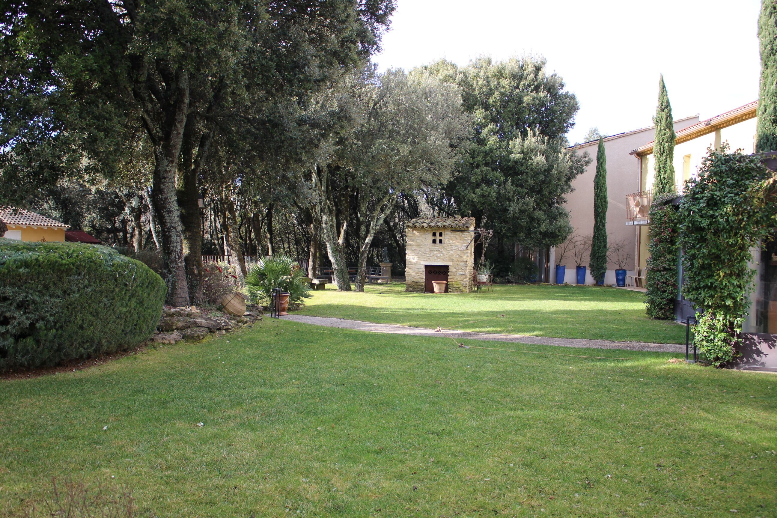 A courtyard with a stone building, surrounded by trees and a well-maintained lawn.