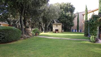 A courtyard with a stone building, surrounded by trees and a well-maintained lawn.