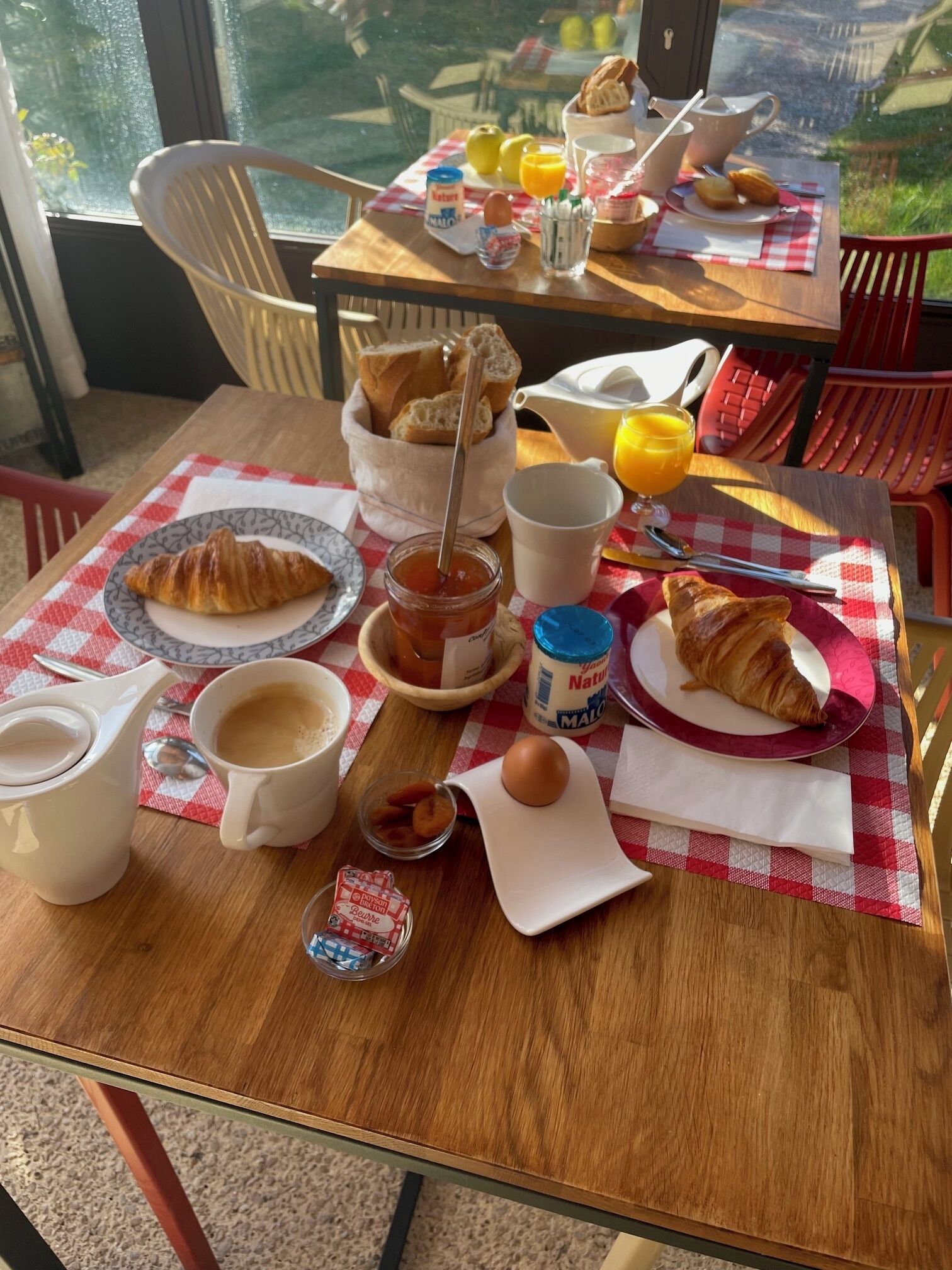 A breakfast table with croissants, coffee, juice, and a bowl of fruit.