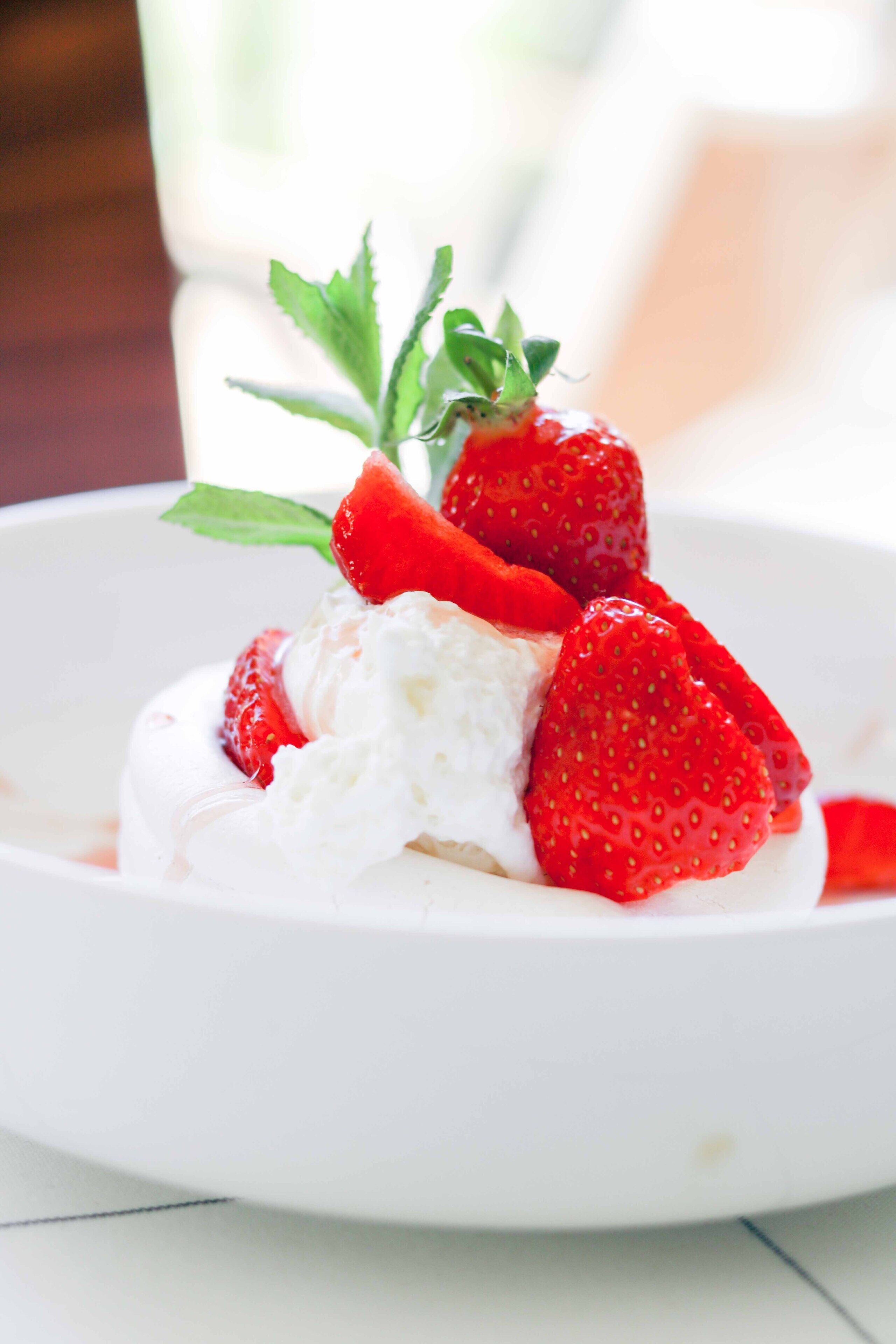 A dessert with strawberries and whipped cream on a white plate.