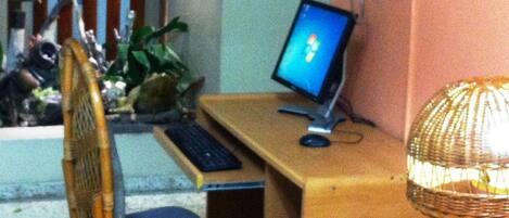 A room with a wooden desk, a computer, a chair, and a lamp.