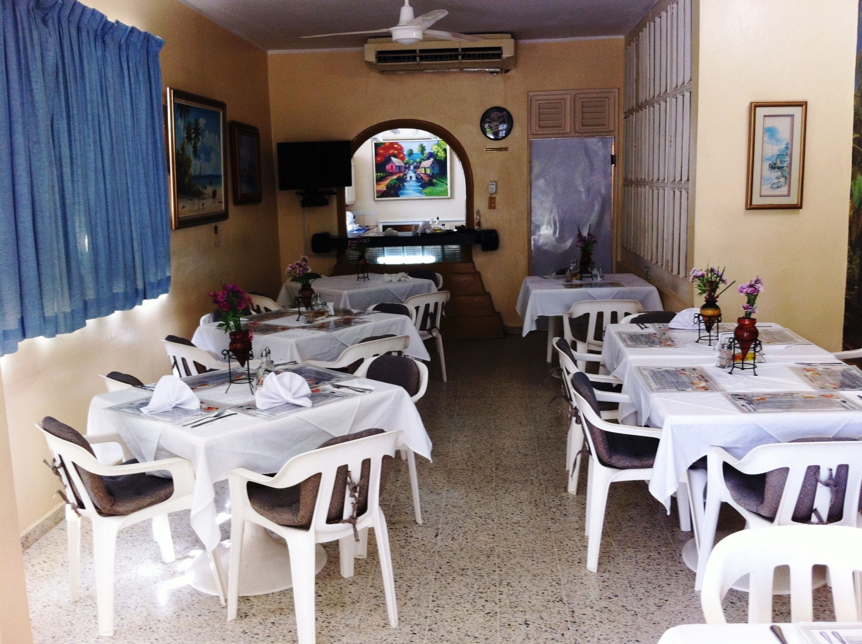 Un espace repas avec des tables dressées, des chaises et un téléviseur fixé au mur.