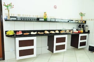 Una cocina con encimera negra, armarios blancos y una variedad de alimentos y utensilios de cocina.