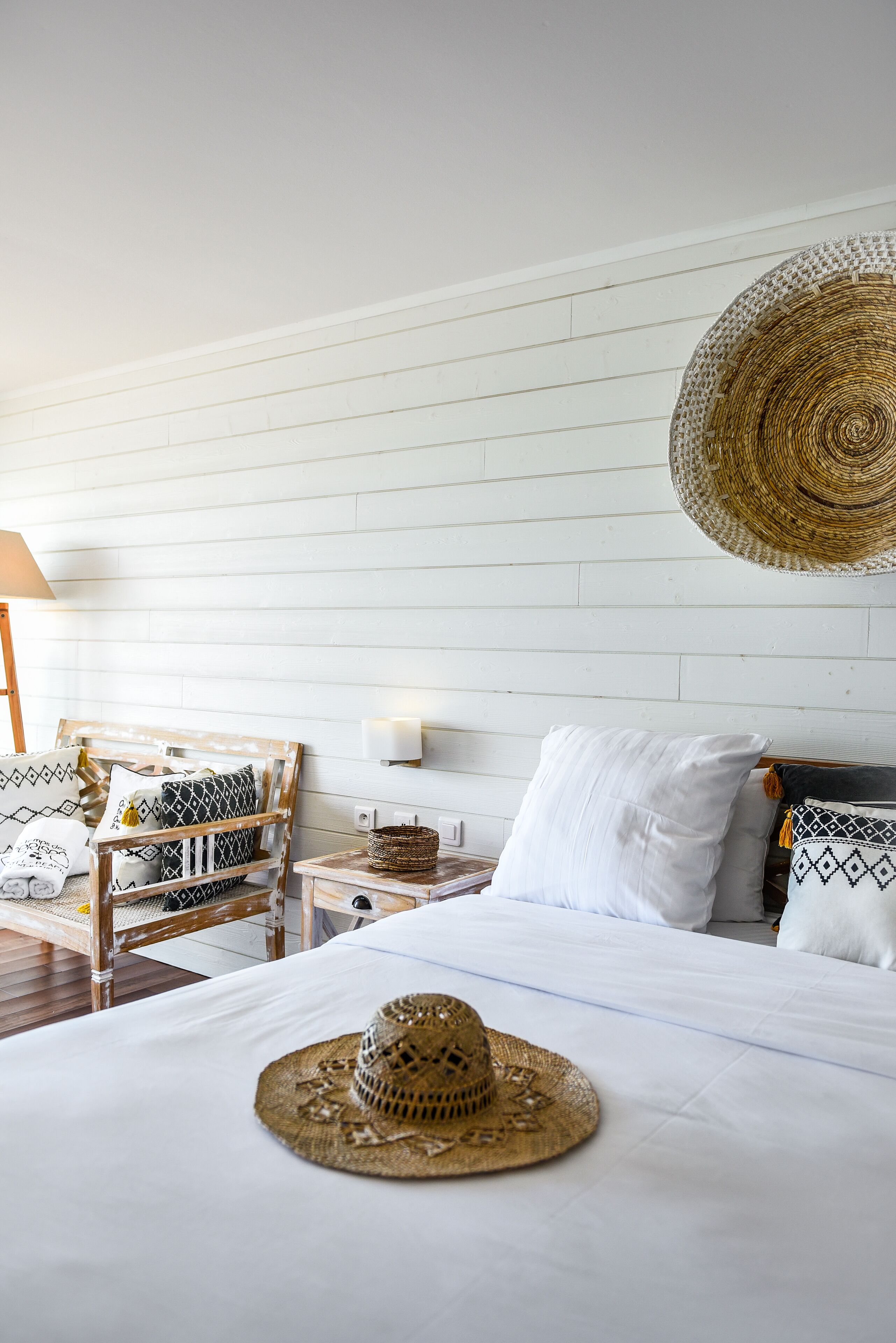 Un dormitorio ordenado con cama, mesitas de noche y una cesta tejida sobre la cama.