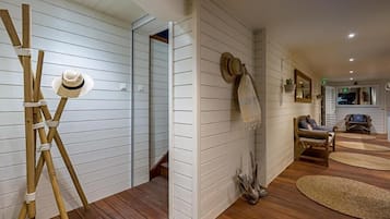 Una habitación con paredes de paneles blancos, suelo de madera, una escalera de madera y un sombrero en la pared.