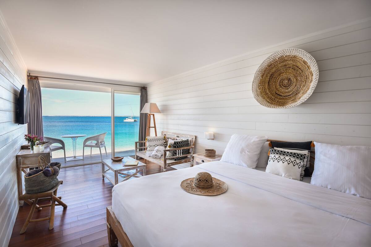 Une chambre d’hôtel avec un lit, une chaise, une table et une vue sur l’océan.