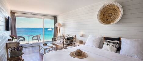 Una habitación de hotel con cama, una silla, una mesa y vista al océano.