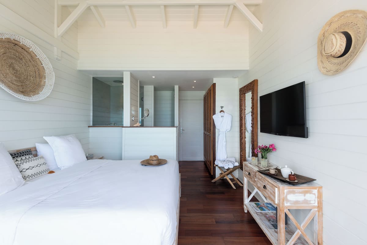 Une chambre à coucher avec un grand lit, une commode en bois, une télévision et un miroir.
