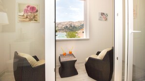 A balcony with wicker chairs, a small table with drinks, and a view of a mountainous landscape. - Heritage hotel Forza (Baska)