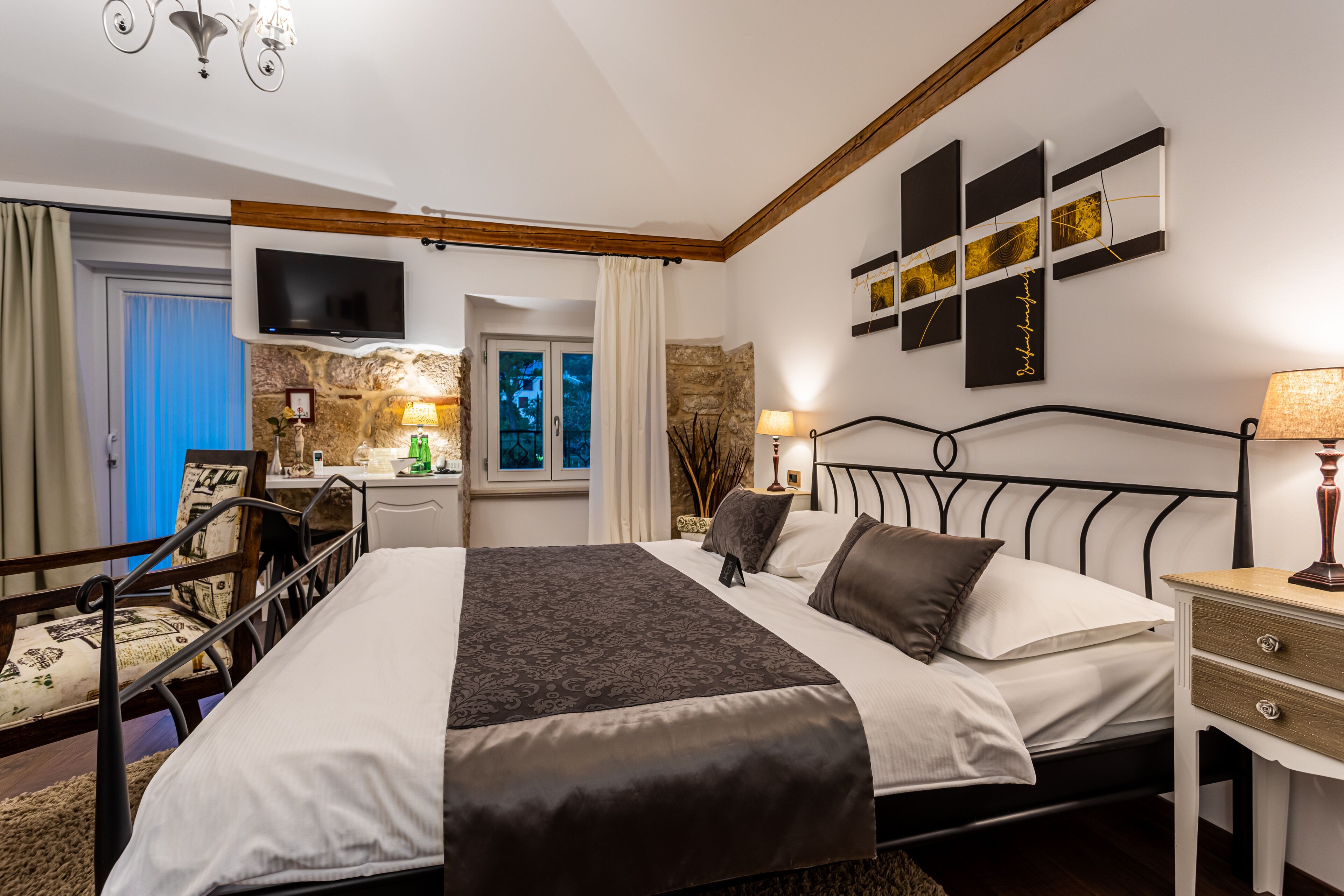 A bedroom with a bed, bedside table, TV, and artwork on the wall.