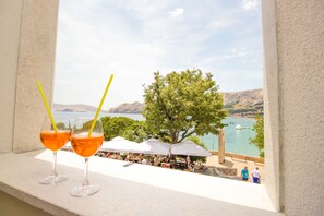 Two glasses of orange beverage on a ledge with a view of a lake and mountains in the background. - Heritage hotel Forza (Baska)