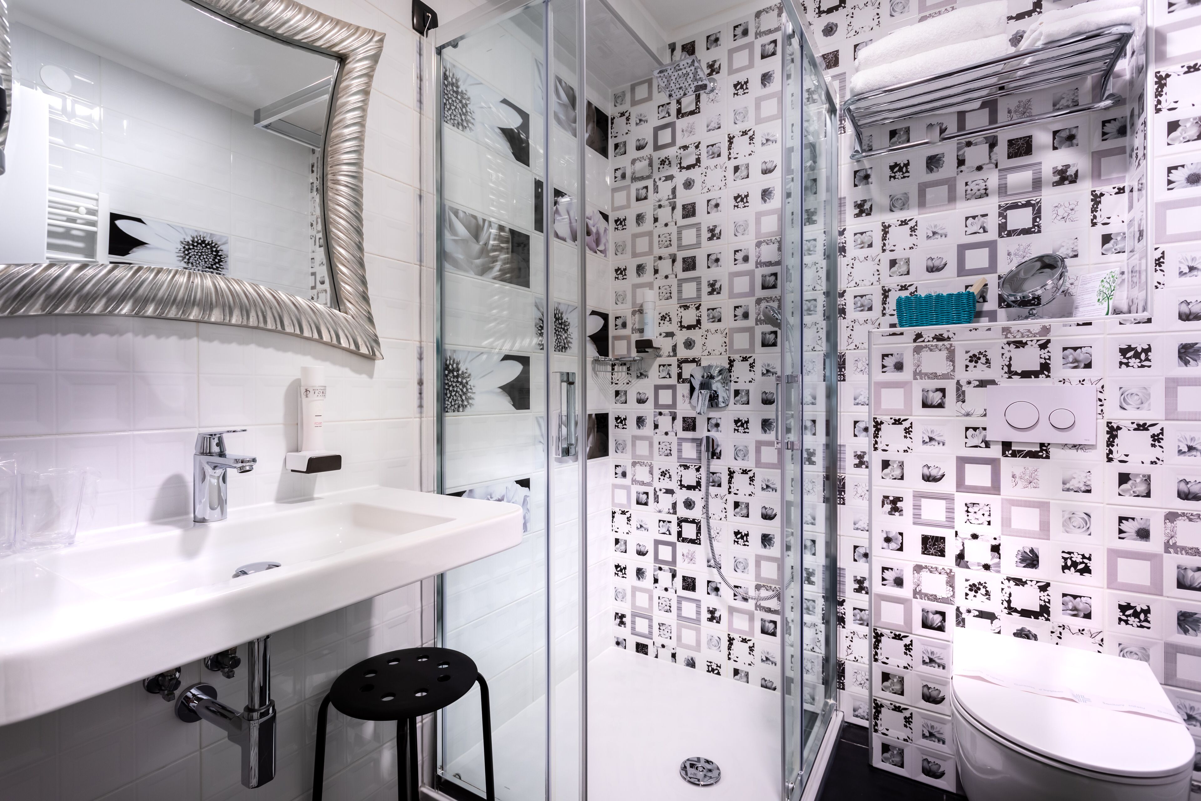 Ein Badezimmer mit einem weißen Waschbecken, einem Spiegel, einer Duschkabine aus Glas und einer Toilette.