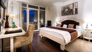 A hotel room with a large bed, a desk with a chair, a television, and a window with curtains. - Heritage hotel Forza (Baska)