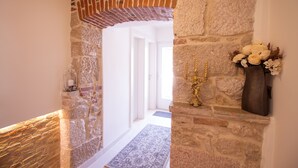 A stone archway leading to a room with a patterned rug and a vase with flowers. - Heritage hotel Forza (Baska)