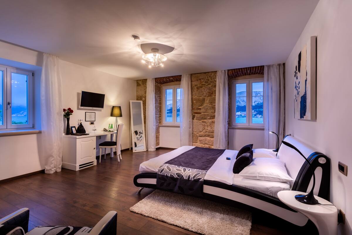 A modern bedroom with a bed, desk, and TV.