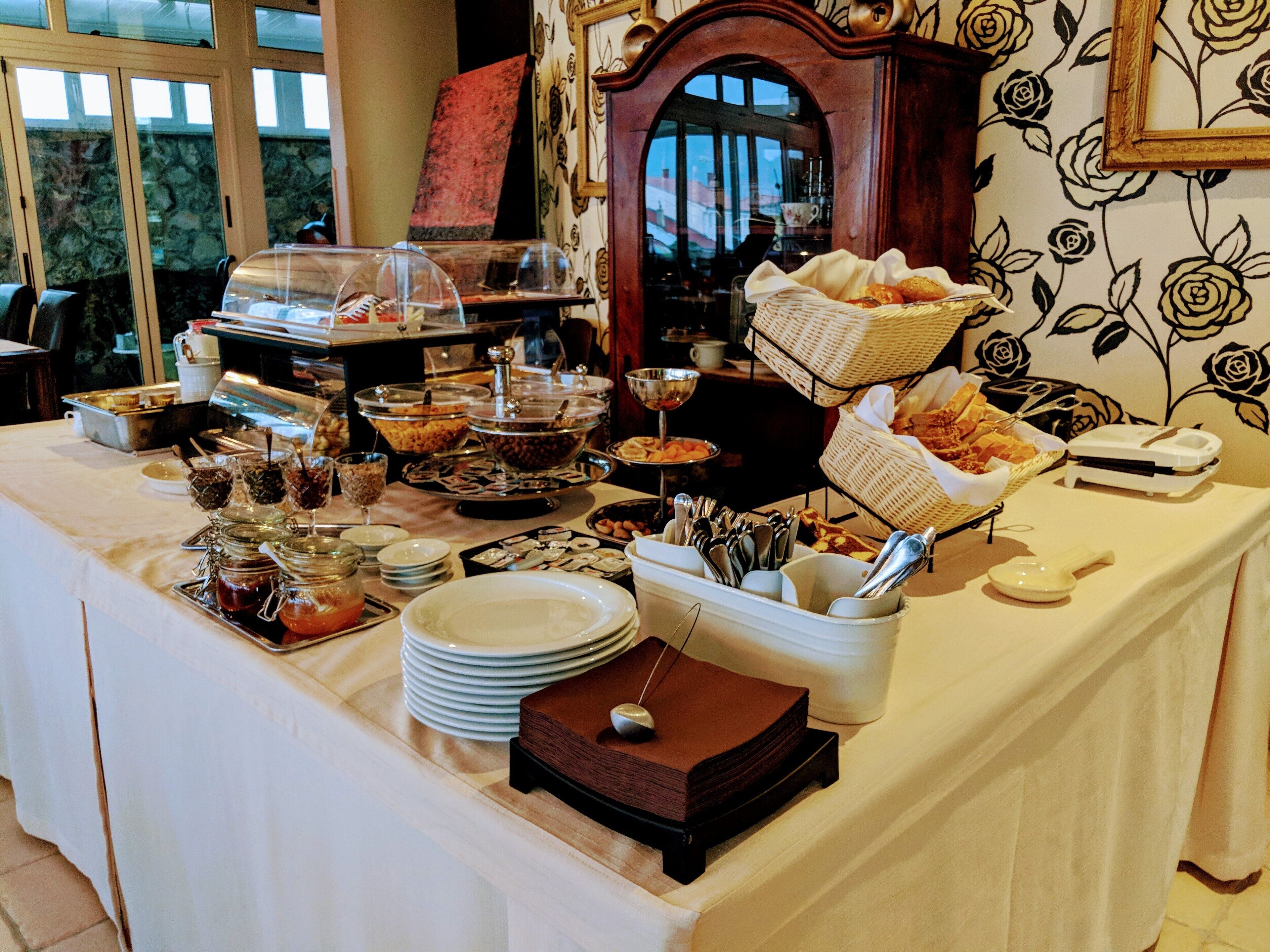 Een buffet met diverse gerechten, waaronder een fruitschaal, een broodmand en een koffiehoek.