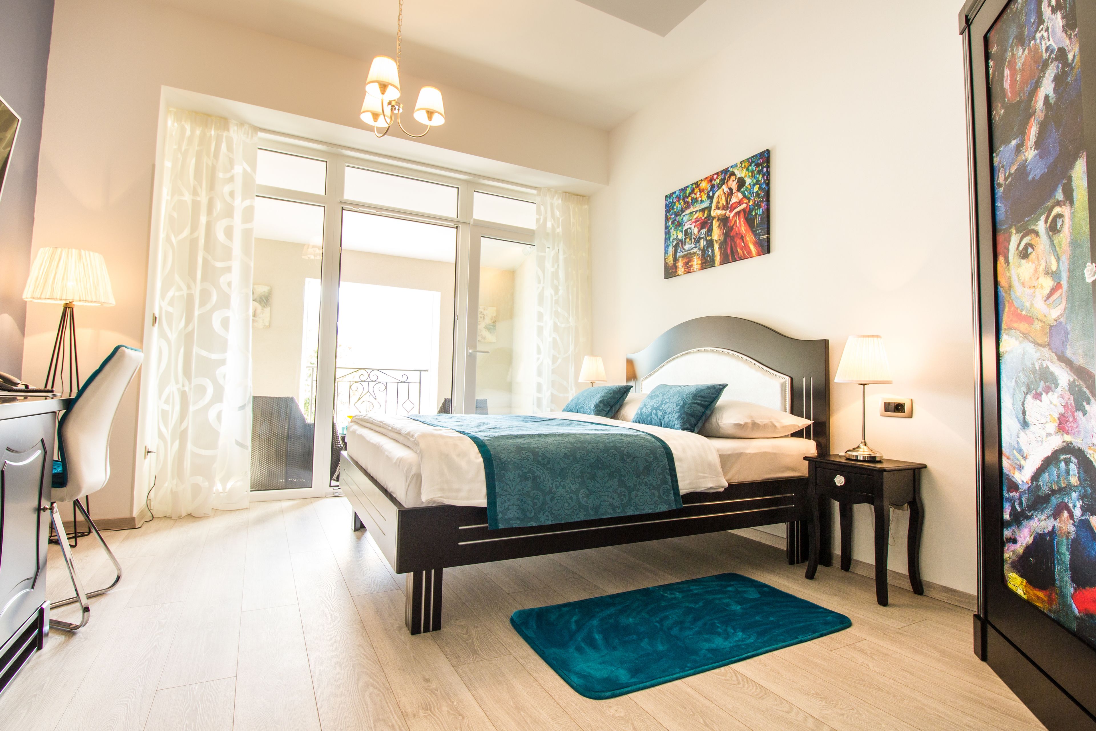 A bedroom with a bed, bedside tables, a desk, and a chair.
