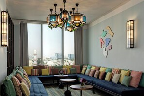 A modern living room with a large sofa, a coffee table, and a city view through large windows.