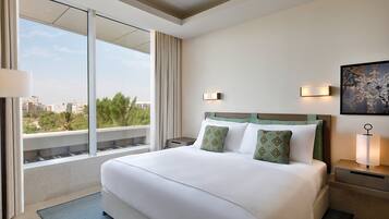 Una camera d'albergo con un letto grande, due comodini, un tavolino e una finestra con vista sulla città, oltre a un quadro appeso al muro.