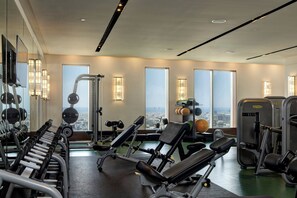 A gym with exercise equipment, large windows, and a view of the city.