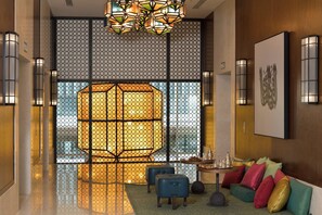 A modern interior with a geometric patterned wall, a seating area with colorful cushions, and a decorative hanging light fixture.