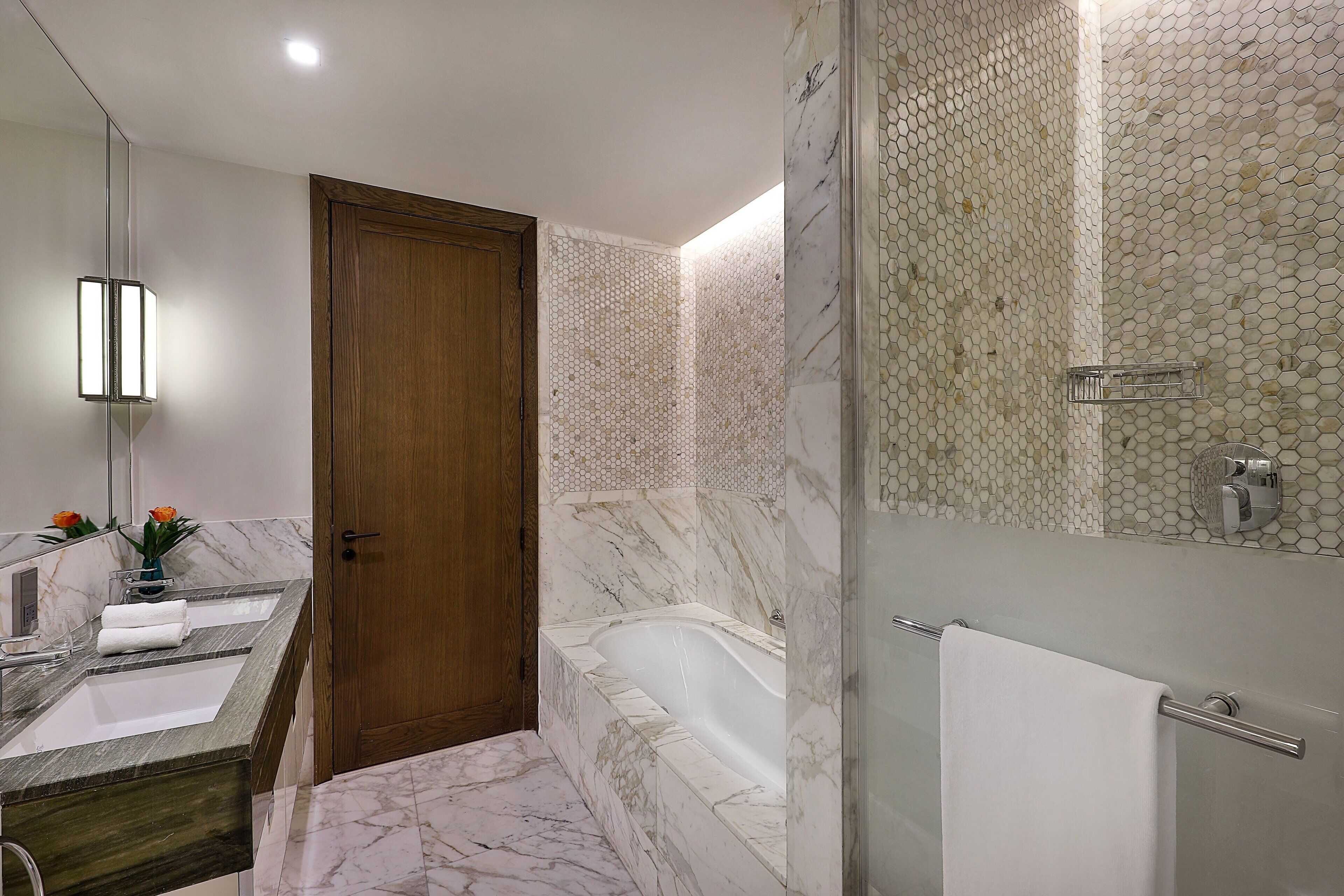 Un baño con lavamanos de mármol, bañera y zona de ducha.