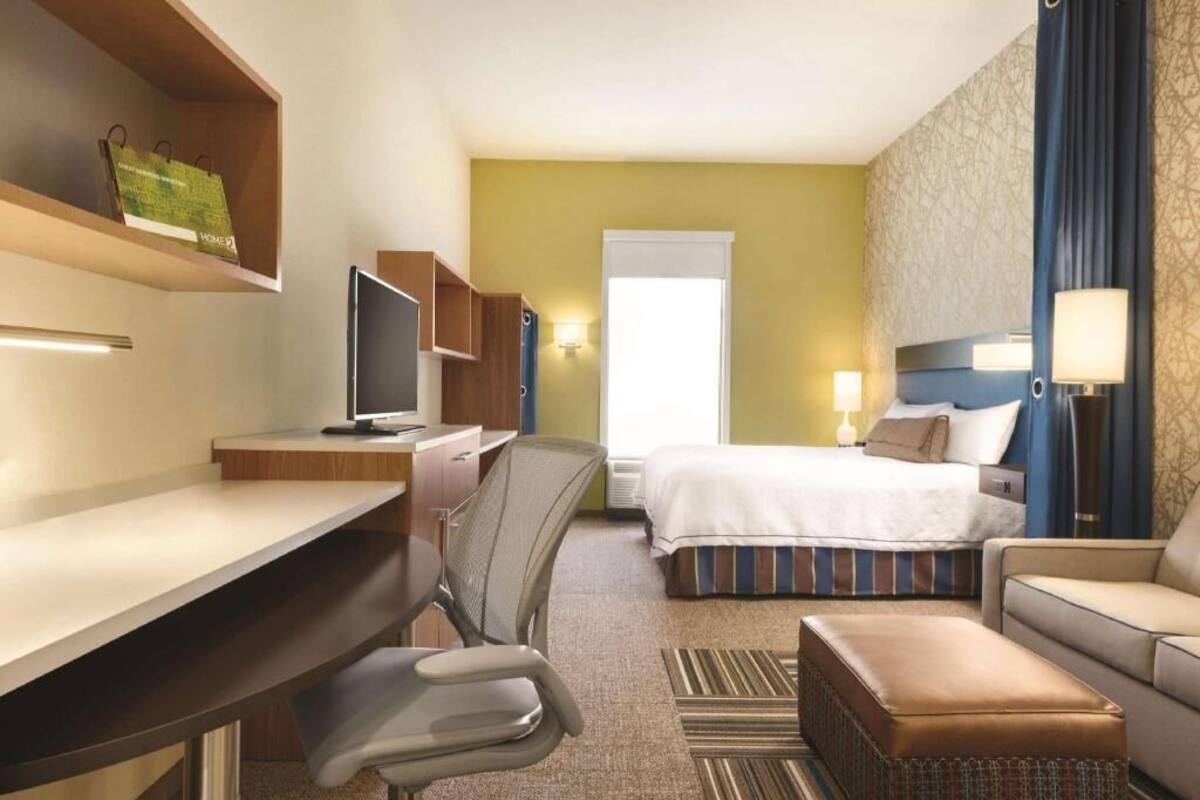 Une chambre d’hôtel équipée d’un bureau, d’une chaise, d’un lit et d’un canapé.