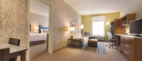 Habitación de hotel con cama, escritorio, silla, sofá, televisor y lámpara.