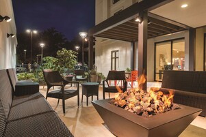 An outdoor seating area with wicker furniture, a fire pit, and ambient lighting.