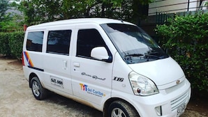 A white van parked on a dirt road with a logo and text on its side. - Hostal Acuarius (Santa Marta)