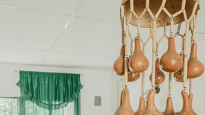 A room with a green curtain, a wooden chair, a TV stand, and a wall-mounted decorative object. - Hostal Acuarius (Santa Marta)