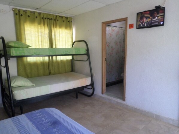 A room with bunk beds, a television, and a door leading to a bathroom. - Hostal Acuarius (Santa Marta)