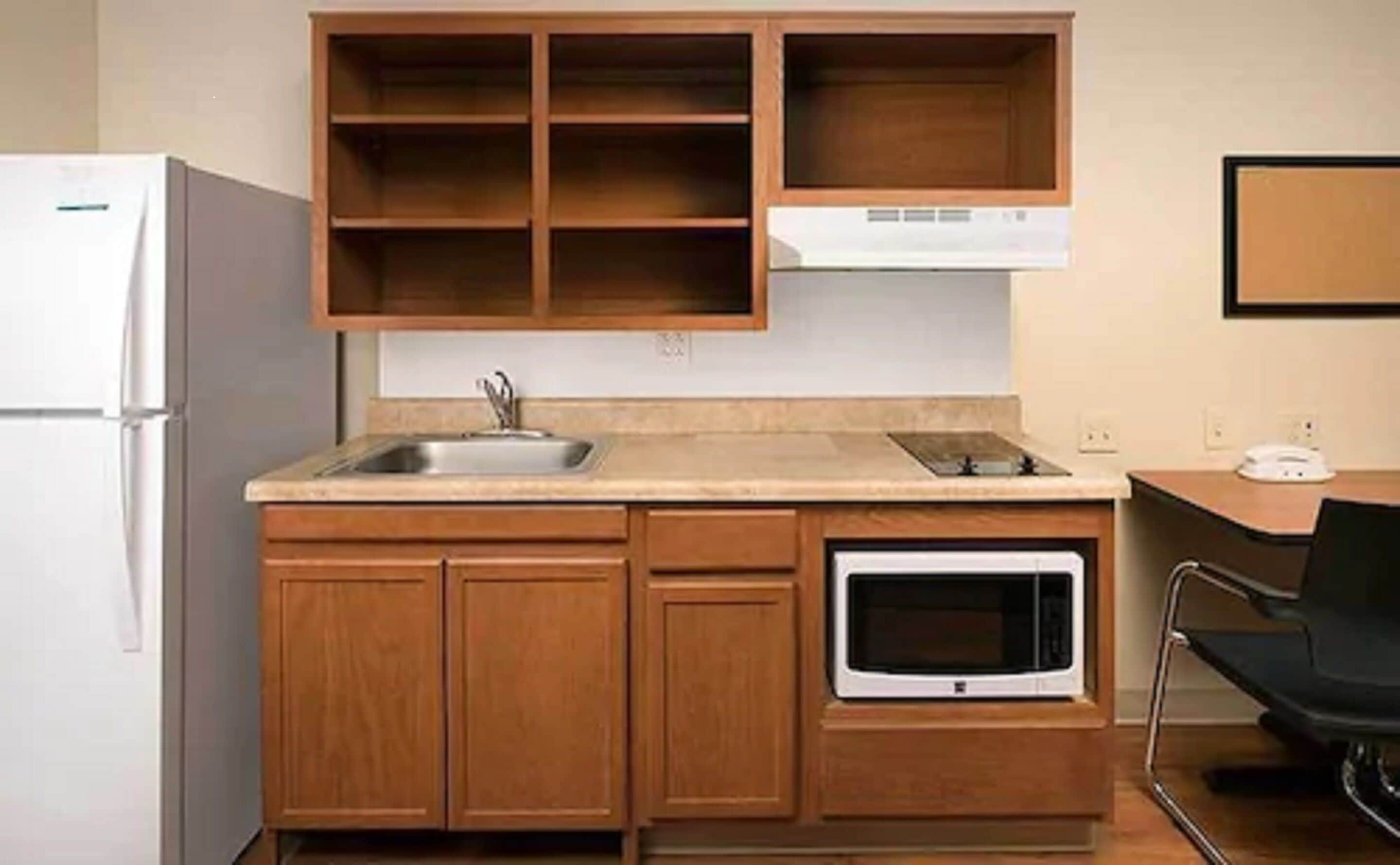 A compact kitchen with a built-in oven, a sink, and wooden cabinets.
