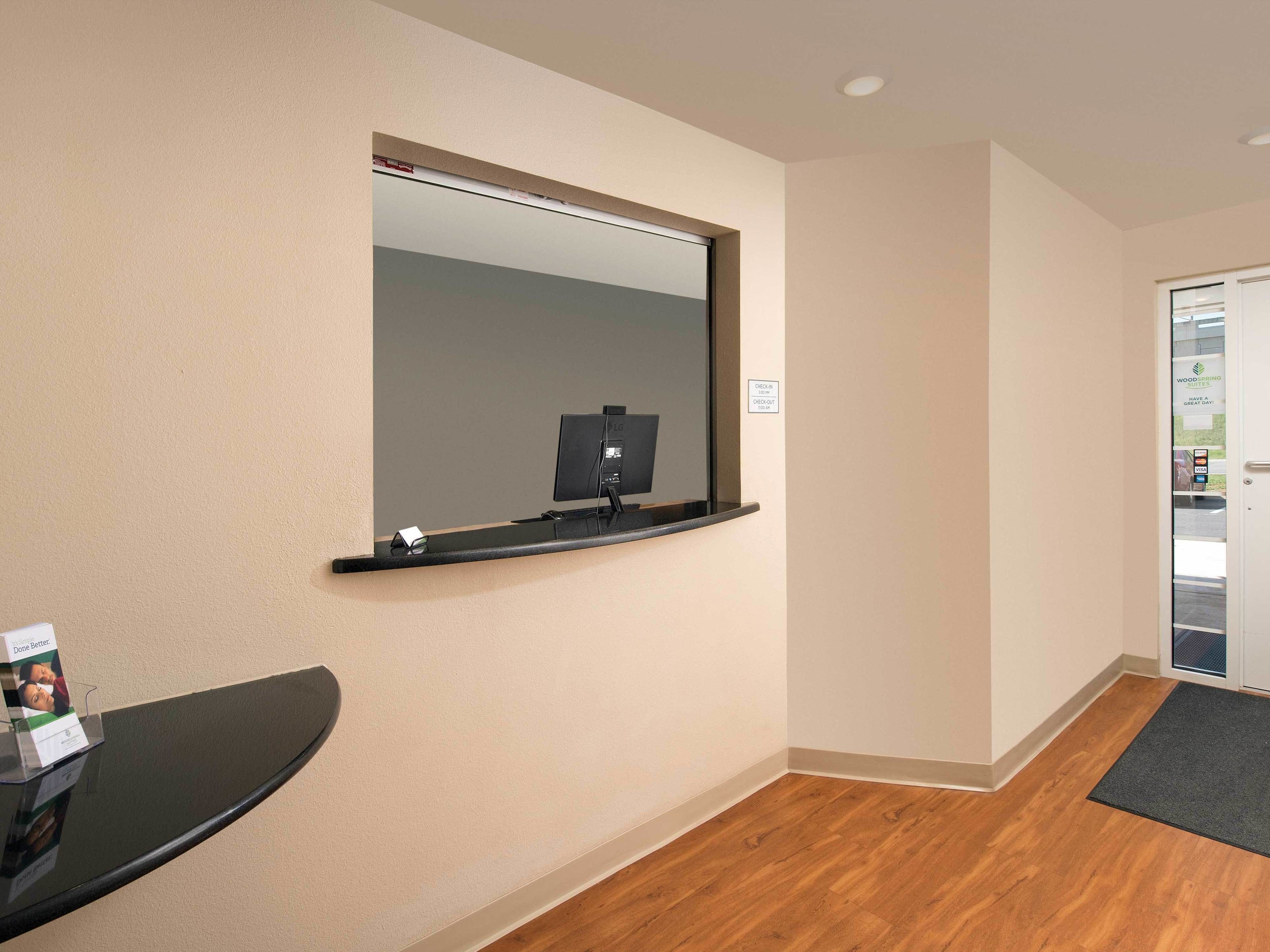A hotel room with a large mirror, a flat-screen TV, a small table with a magazine, and a door leading to the outside.
